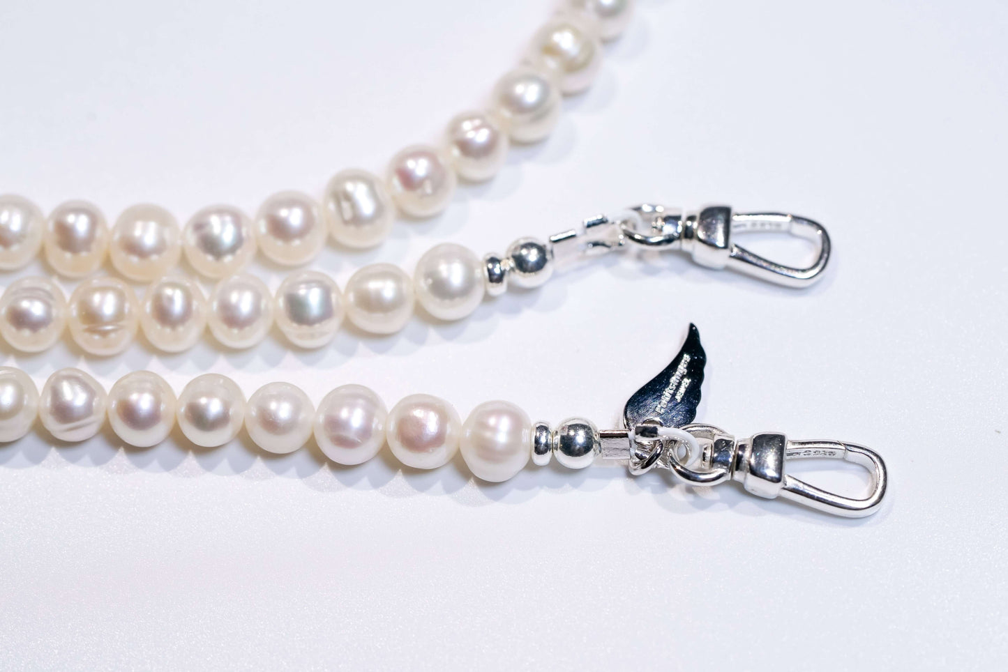 Classic pearl cross-body phone strap with silver clasps, showcasing natural luster and elegant design.