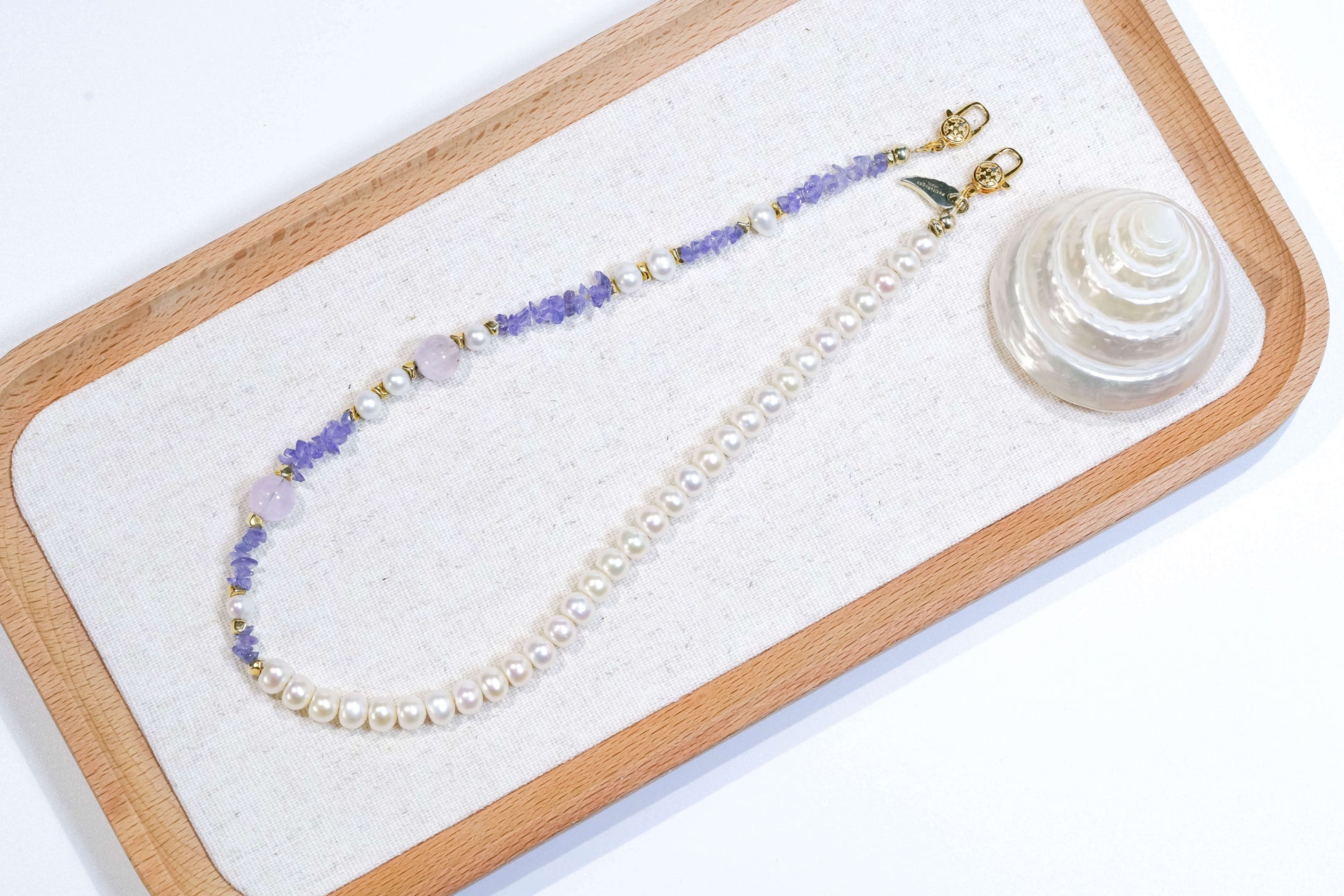 Pearl-Tanzanite-Lavender Amethyst-Silver Phone Charm/Bracelet elegantly displayed on a wooden tray.