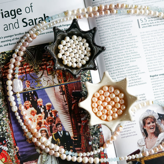 Freshwater pearl necklaces and loose pearls displayed over an open magazine.