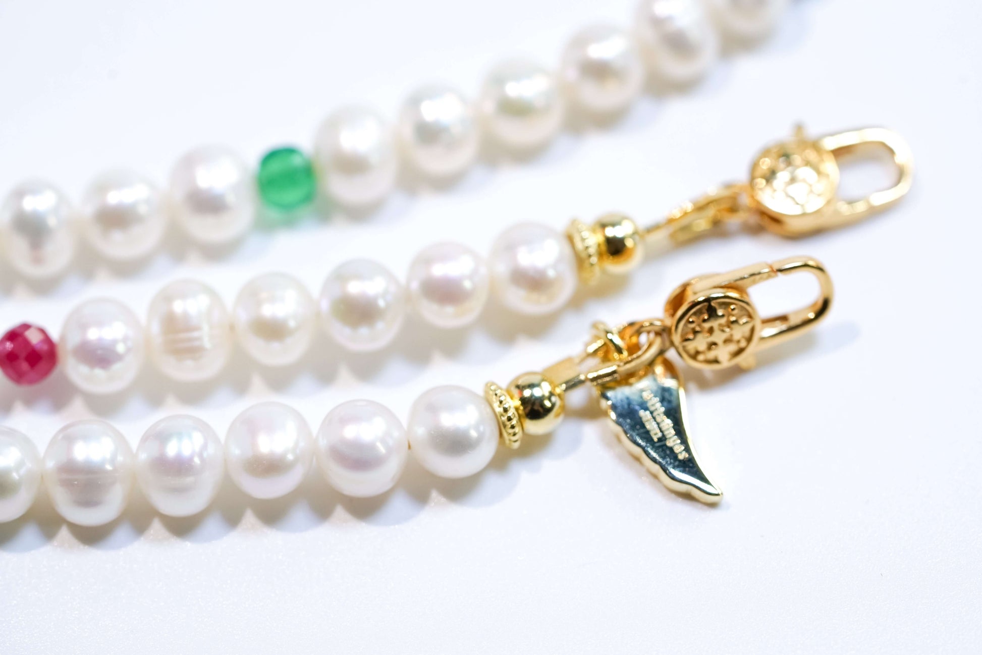 Multi-gemstone pearl phone strap with freshwater pearls, ruby, green agate, lazurite, and turquoise, featuring gold-plated hardware.