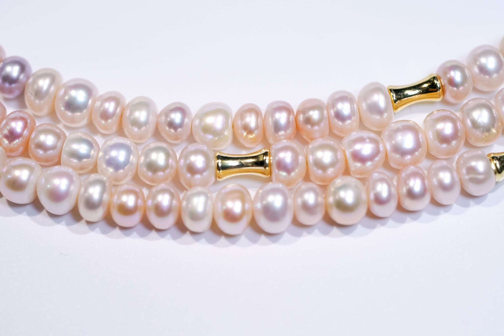 Close-up of candy-colored natural pearls with gold accents on a cross-body phone strap necklace.