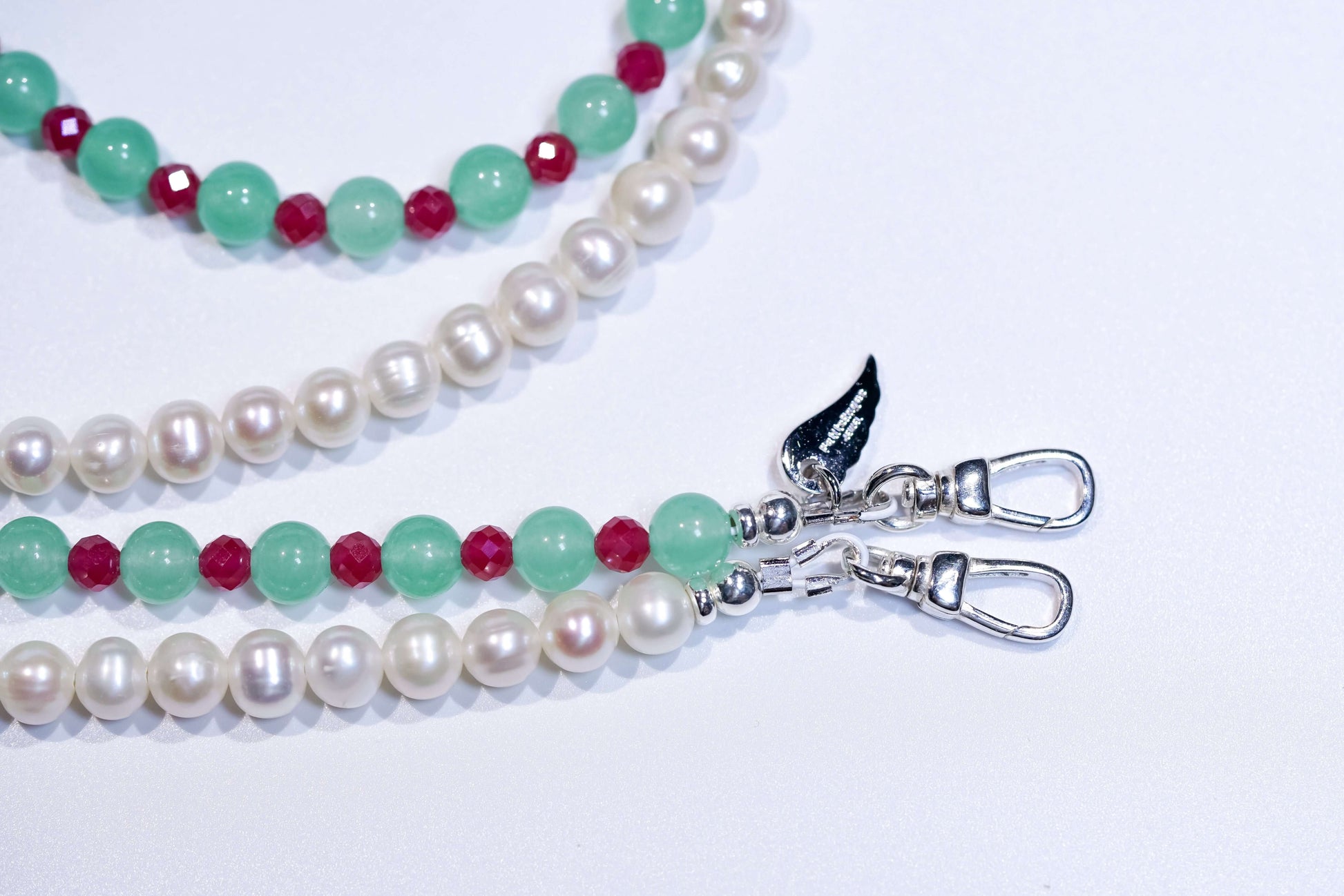 Pearl and aventurine cross-body phone strap/necklace with ruby accents and silver clasps on a white background.