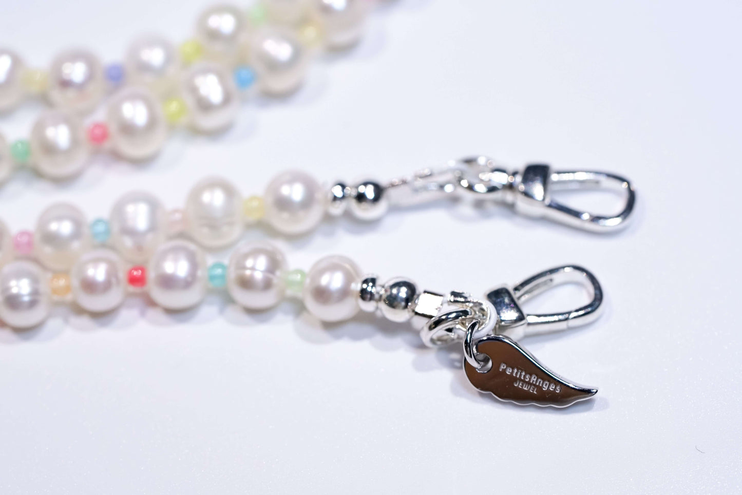 Pearl-glass beads cross-body phone strap with silver hardware and colorful accents close-up.