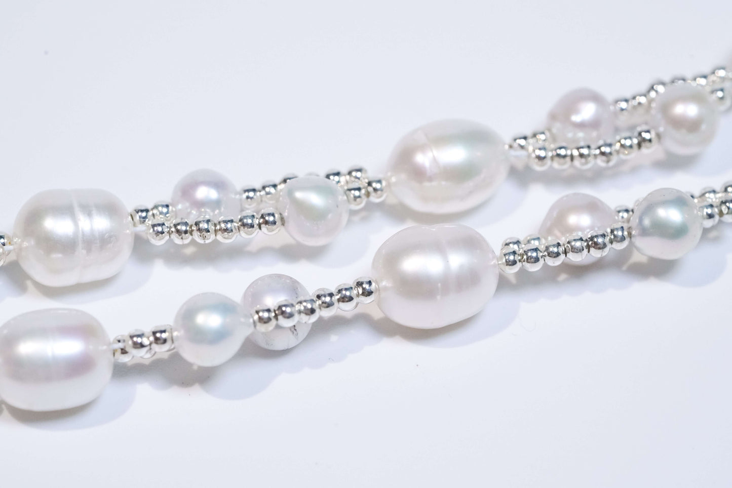 Close-up of natural fresh pearls and S925 silver beads, showcasing a two-way phone strap and bracelet design.